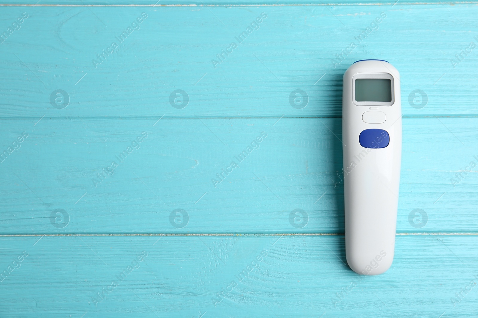 Photo of Modern non contact thermometer on light blue wooden table, top view. Space for text