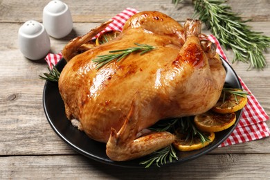 Photo of Tasty roasted chicken with rosemary and lemon on wooden table