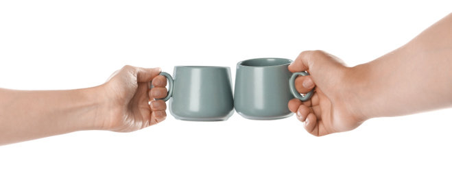 Photo of Women clinking grey cups on white background, closeup