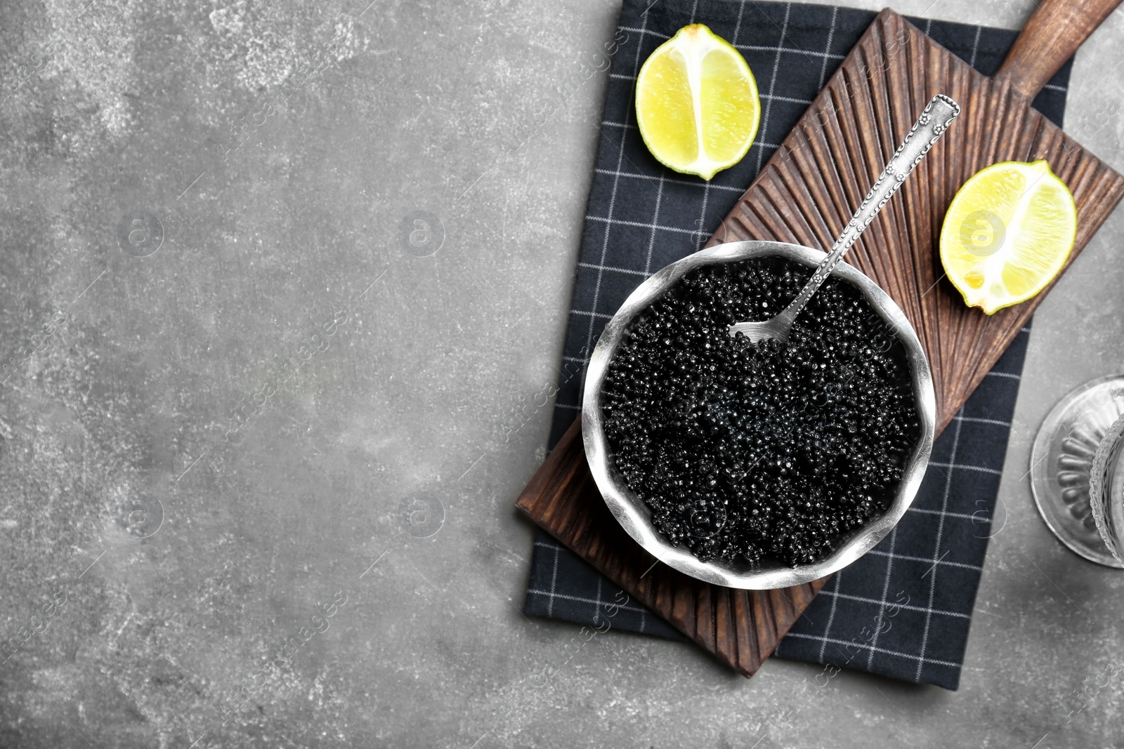 Photo of Metal bowl with black caviar on grey background