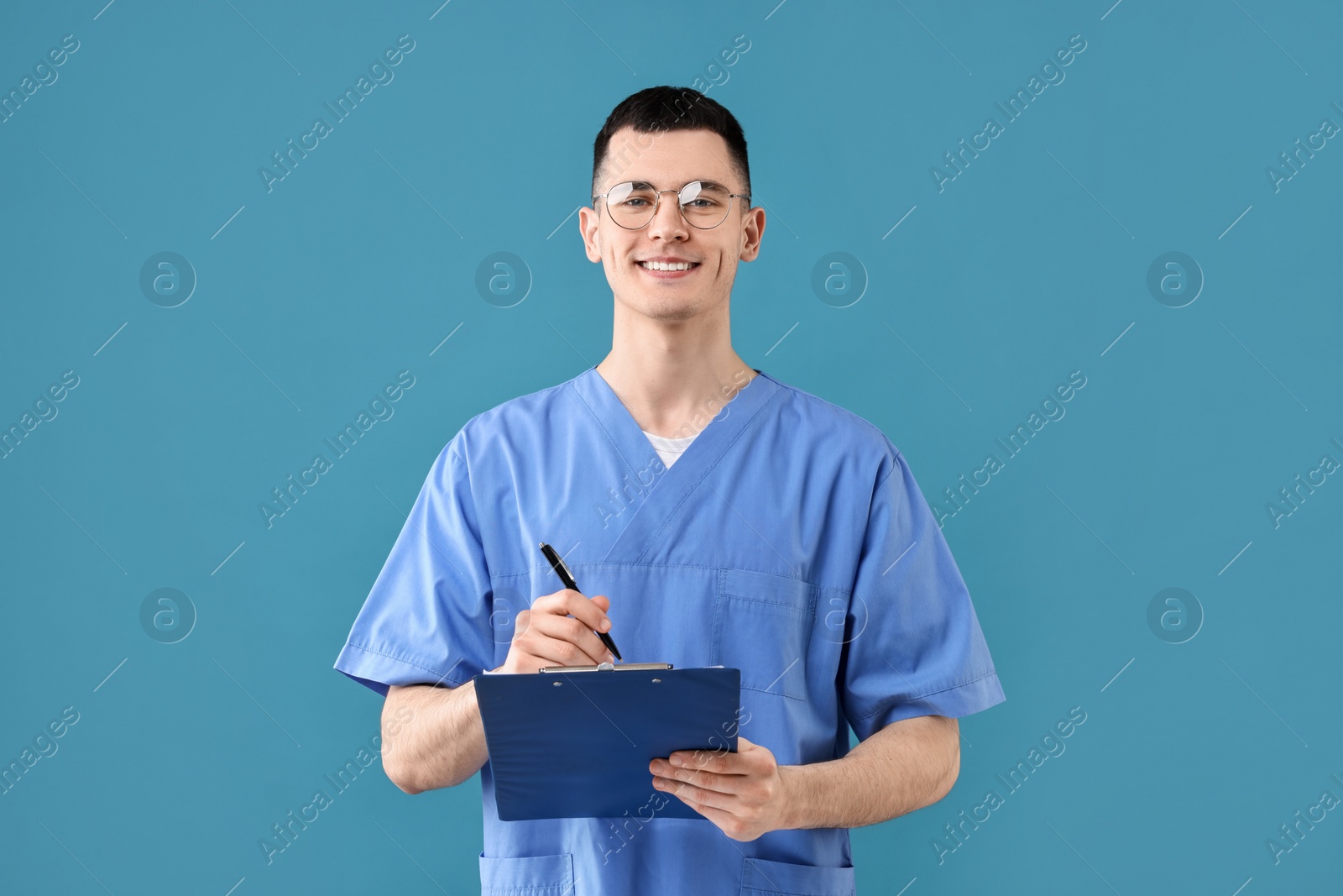 Photo of Portrait of smiling medical assistant with clipboard on light blue background