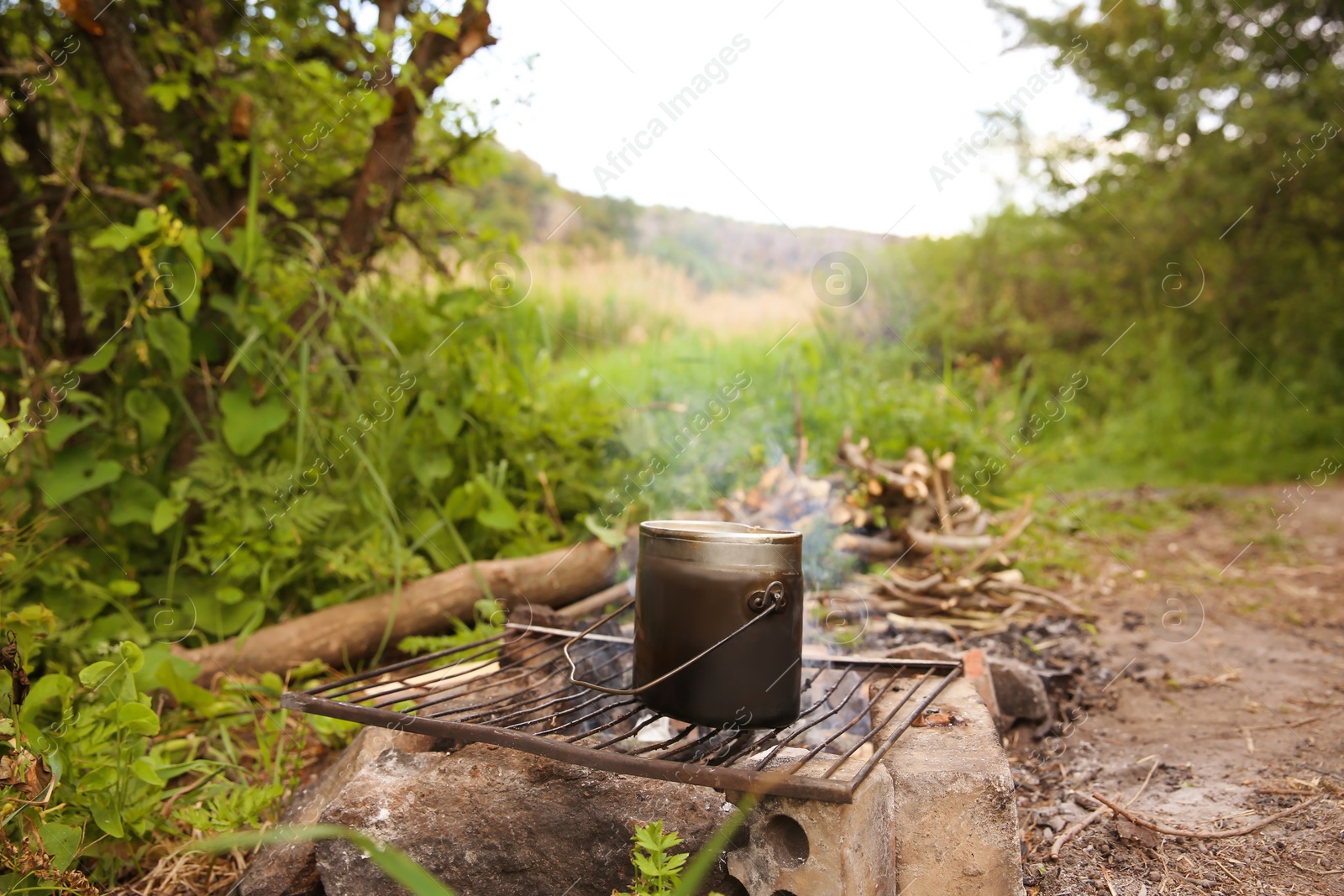 Photo of Cooking food on rack over bonfire in wilderness