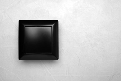 Photo of Black light switch on grey background, top view. Space for text