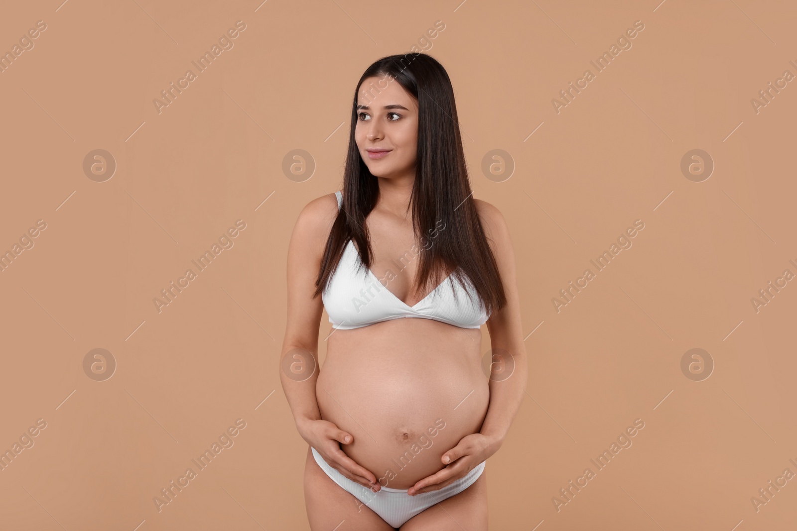 Photo of Beautiful pregnant woman in stylish comfortable underwear on beige background