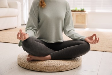 Photo of Woman meditating on wicker mat at home, closeup