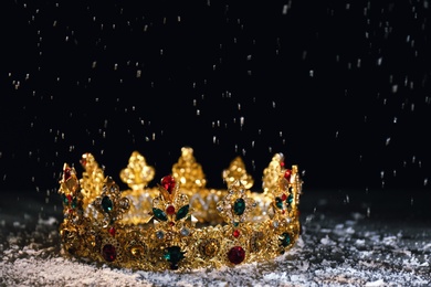 Photo of Beautiful golden crown with gems on black table. Fantasy item