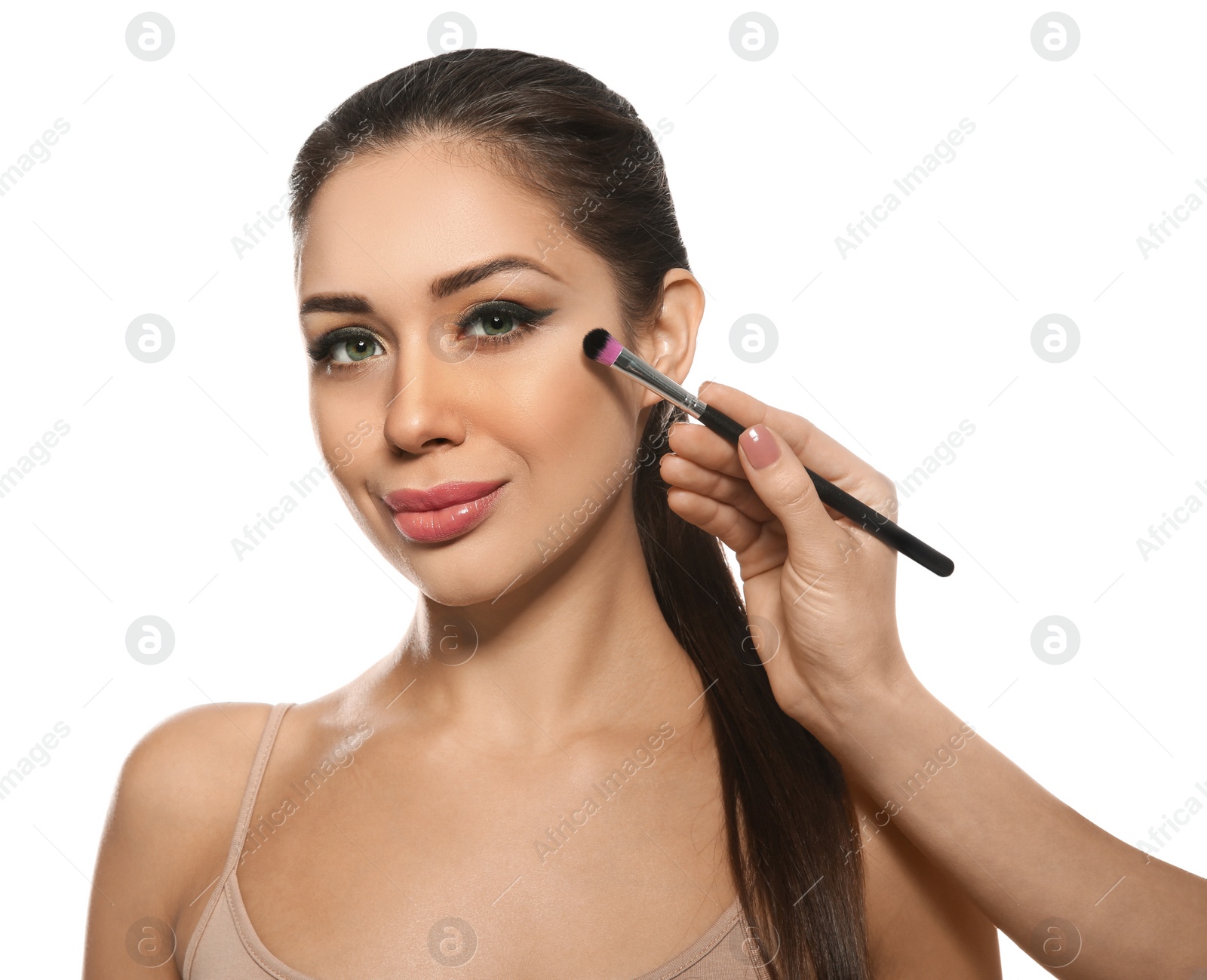 Photo of Artist applying makeup onto woman's face on white background