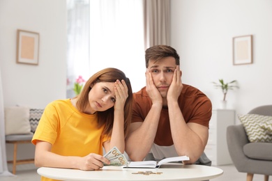 Photo of Sad couple counting money in living room