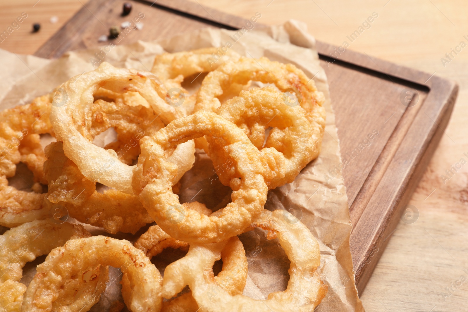 Photo of Homemade crunchy fried onion rings on wooden board, closeup