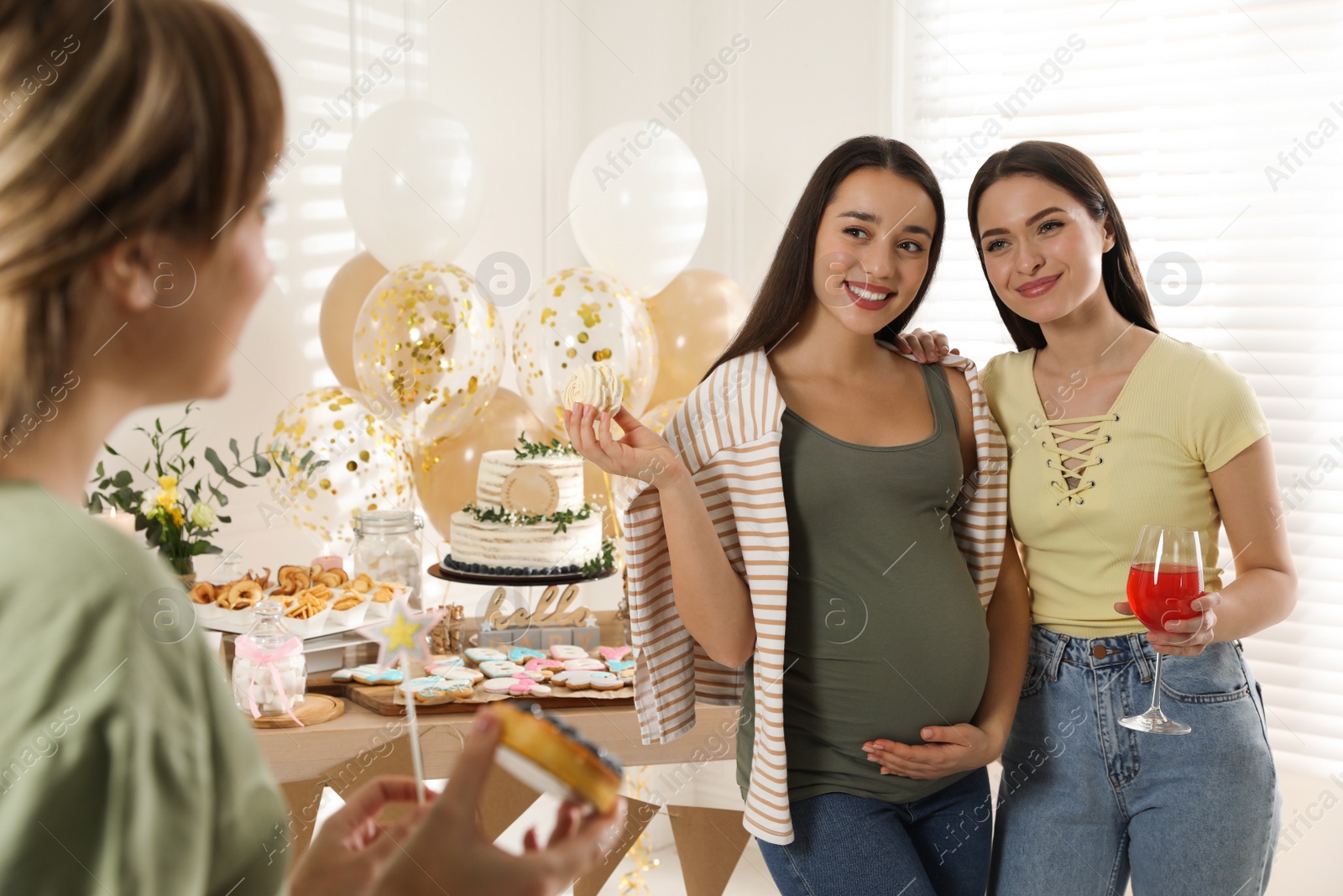 Photo of Happy pregnant woman and her friends with tasty treats at baby shower party