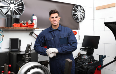 Man near car disk lathe machine at tire service