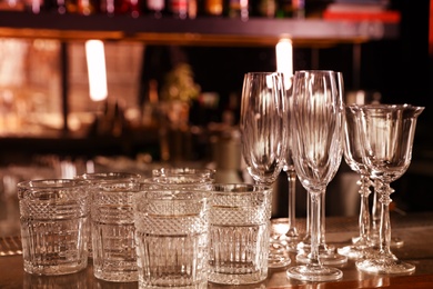 Photo of Different empty clean glasses on counter in bar