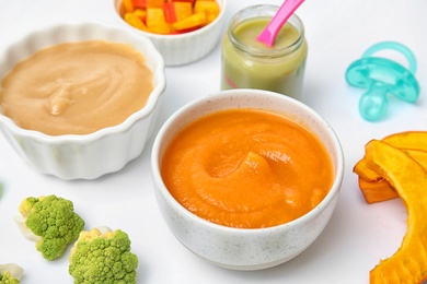 Photo of Bowls with healthy baby food on white background