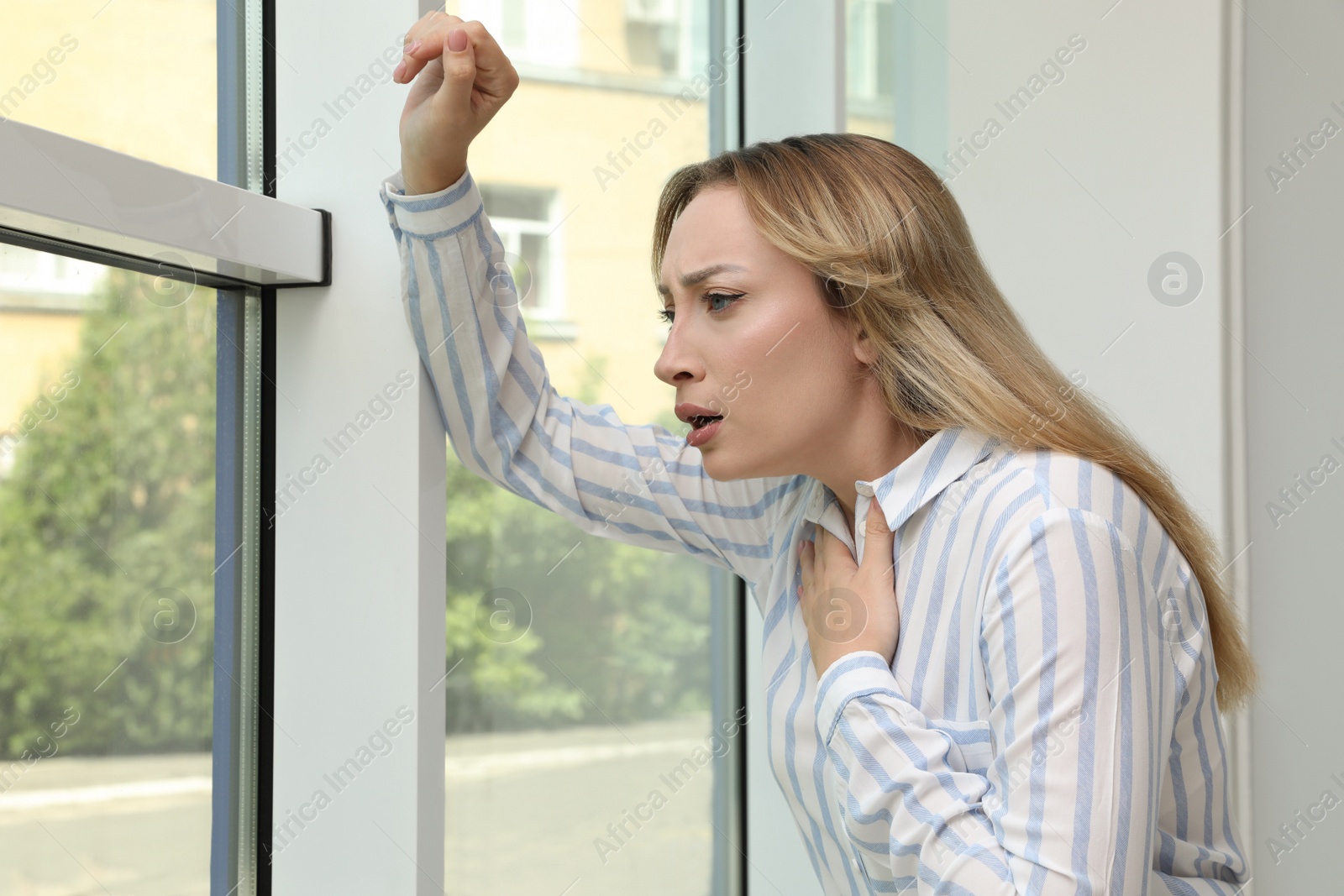 Photo of Young woman suffering from pain during breathing near window