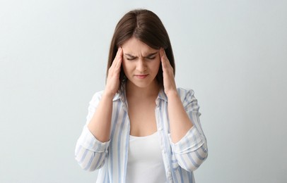 Young woman suffering from migraine on white background