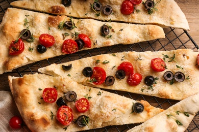 Photo of Focaccia bread with olives and tomatoes on wooden table, closeup