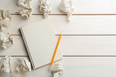 Photo of Notebook, pencil and crumpled sheets of paper on white wooden background, flat lay. Space for text