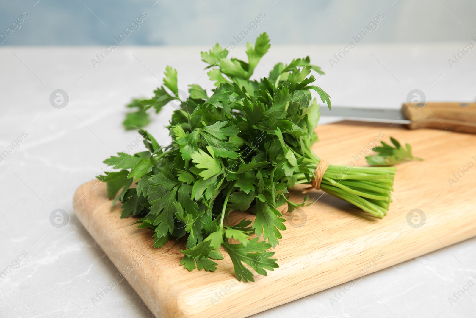 Photo of Wooden board with fresh green parsley on table, closeup