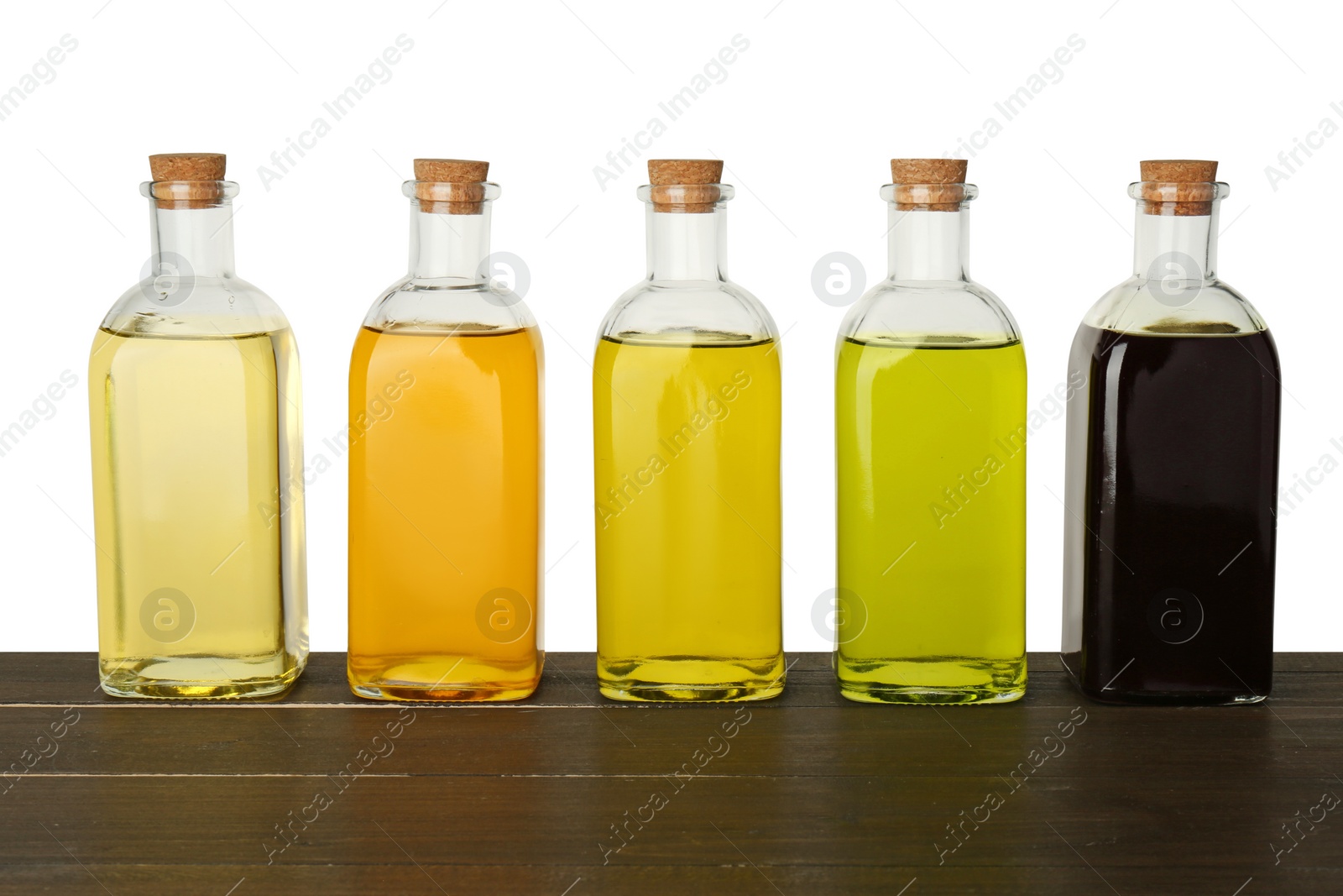 Photo of Vegetable fats. Bottles of different cooking oils on wooden table against white background