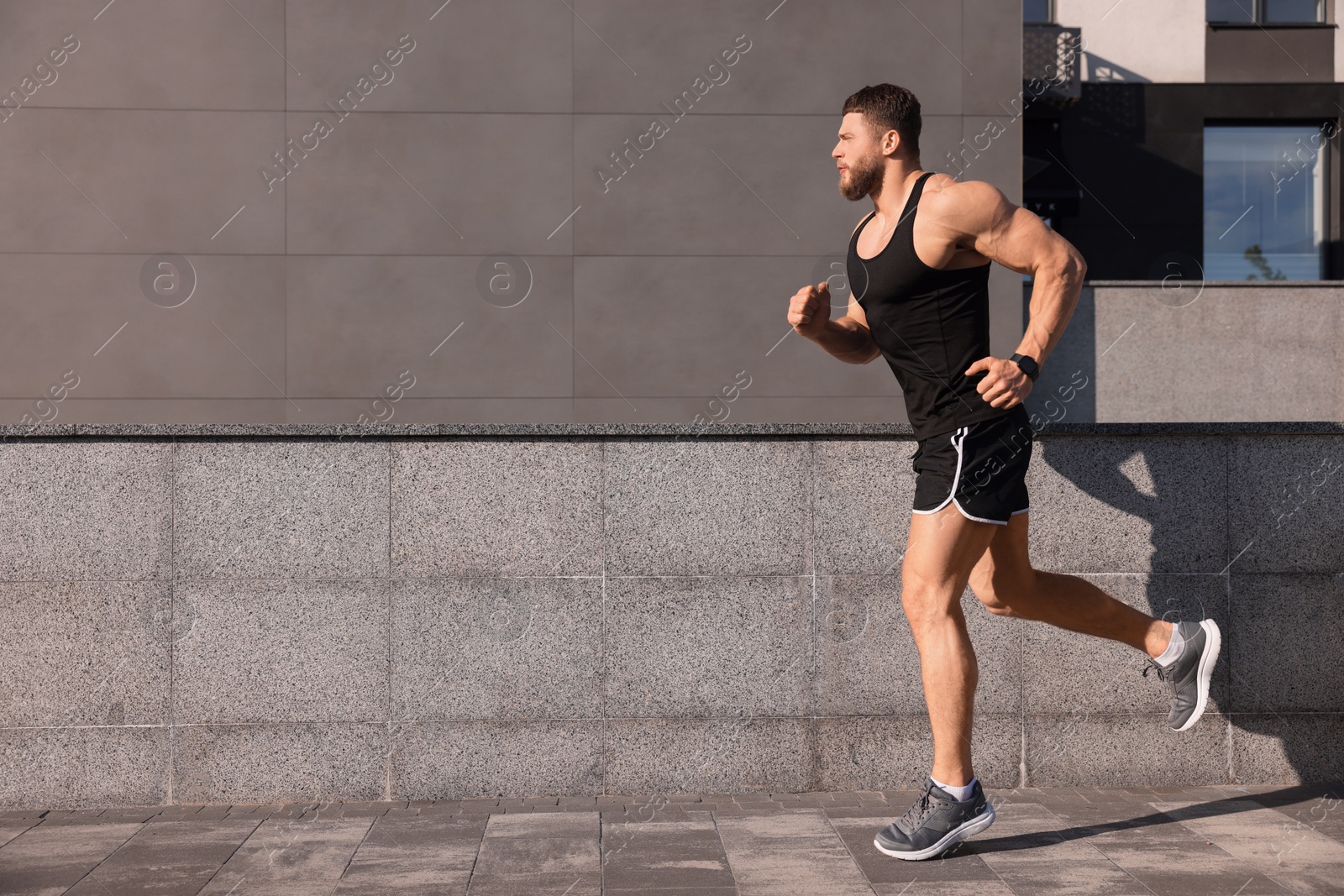 Photo of Young man running near building outdoors. Space for text