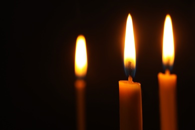 Burning candles on dark background, space for text. Symbol of sorrow