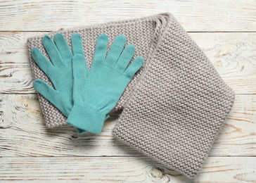 Photo of Gray knitted scarf and gloves on light wooden table, top view