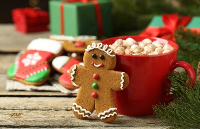 Photo of Tasty gingerbread man cookie and cocoa with marshmallows on wooden table. Space for text