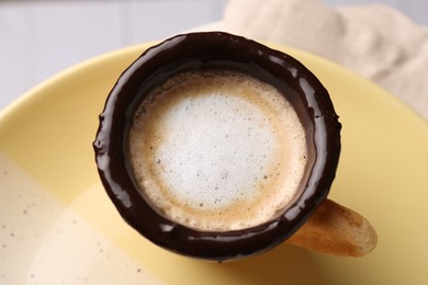 Delicious edible biscuit cup with coffee on plate, closeup