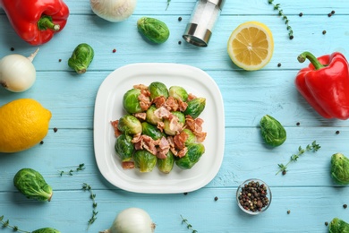 Photo of Flat lay composition of tasty roasted Brussels sprouts with bacon on light blue wooden table