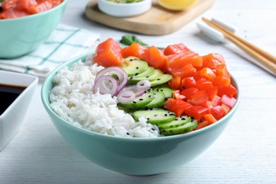 Delicious poke bowl with salmon and vegetables served on white wooden table,closeup
