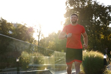 Photo of Happy man running outdoors on sunny day. Space for text