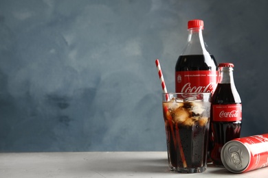 MYKOLAIV, UKRAINE - NOVEMBER 15, 2018: Bottles, glass and can with Coca Cola on table against color background. Space for text