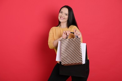 Photo of Beautiful overweight woman with shopping bags on red background