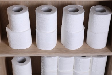 Stacked toilet paper rolls on wooden shelves