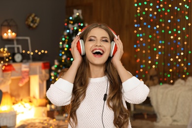 Photo of Happy young woman listening to Christmas music at home