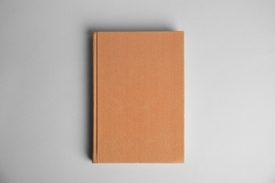 Hardcover book on light grey background, top view. Space for design