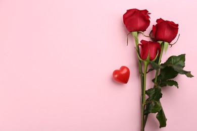 Photo of Beautiful red roses and decorative heart on pink background, flat lay with space for text. Valentine's Day celebration