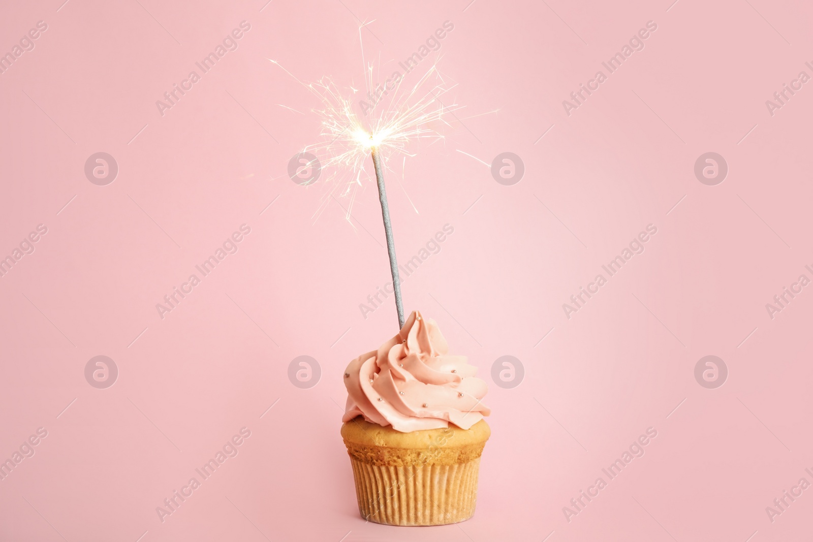 Photo of Birthday cupcake with sparkler on pink background