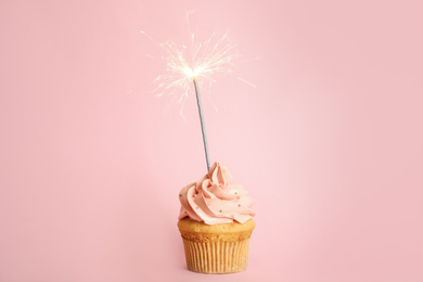 Photo of Birthday cupcake with sparkler on pink background