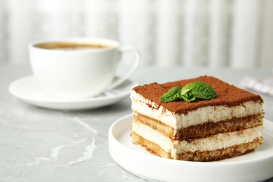 Photo of Tiramisu cake with cup on table against light background, space for text