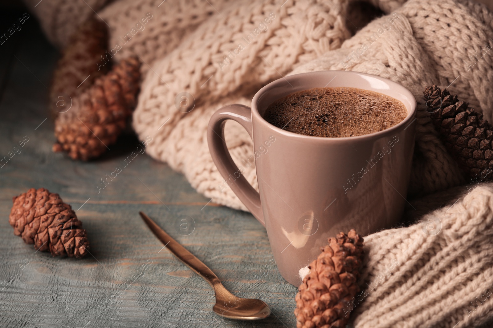 Photo of Composition with cup of hot cozy drink and autumn sweater on table. Space for text