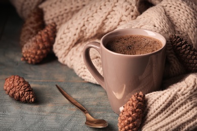 Photo of Composition with cup of hot cozy drink and autumn sweater on table. Space for text