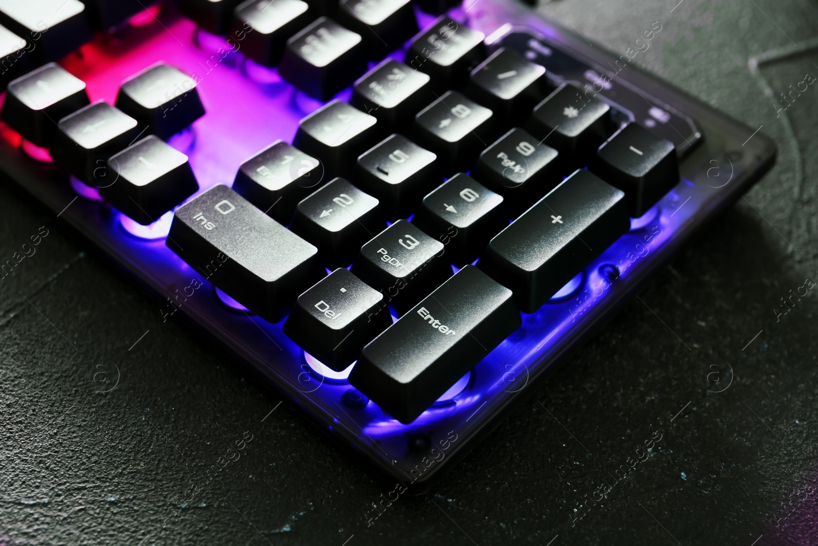 Photo of Modern keyboard with RGB lighting on grey table, closeup