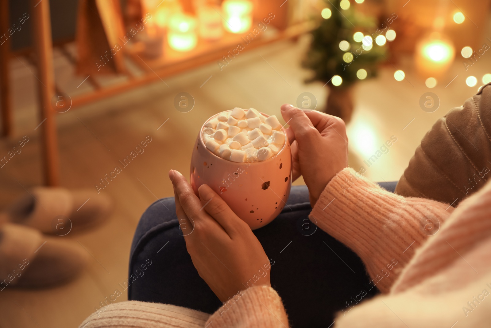 Photo of Woman holding cup of hot drink with marshmallows at home, closeup. Magic Christmas atmosphere