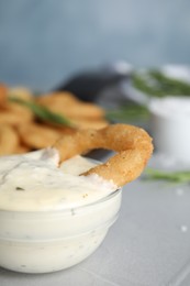 Photo of Fried onion ring with sauce on grey table