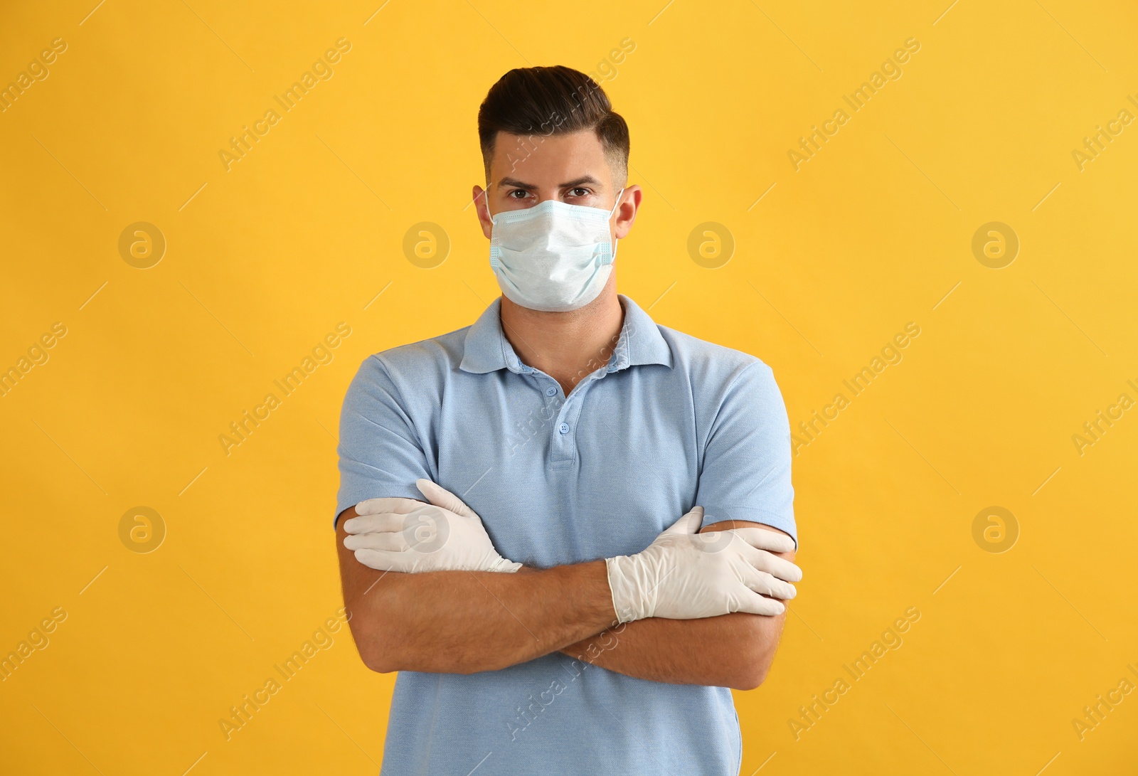 Photo of Man wearing protective face mask and medical gloves on yellow background
