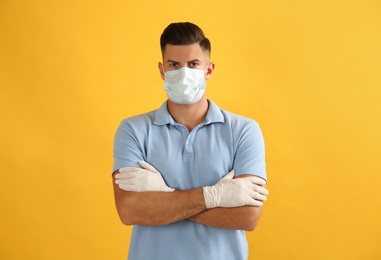 Man wearing protective face mask and medical gloves on yellow background