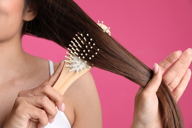 Woman with hair brush on color background, closeup