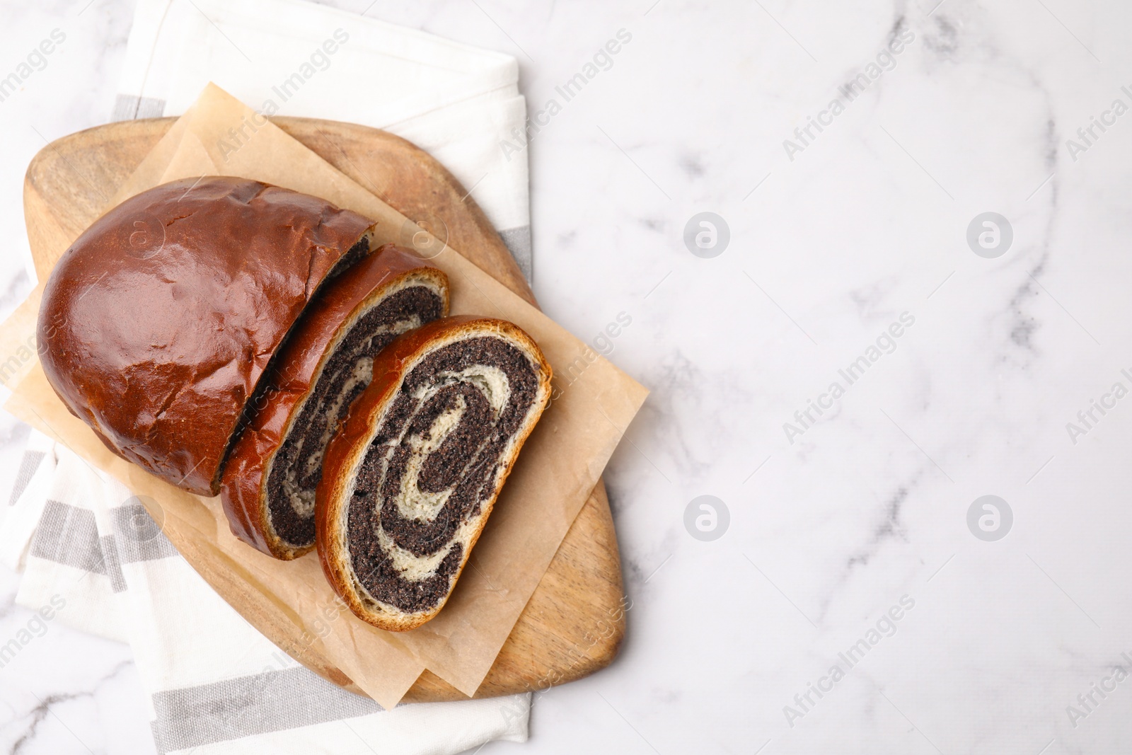 Photo of Cut poppy seed roll on white marble table, top view with space for text. Tasty cake