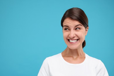 Portrait of embarrassed young woman on light blue background, space for text